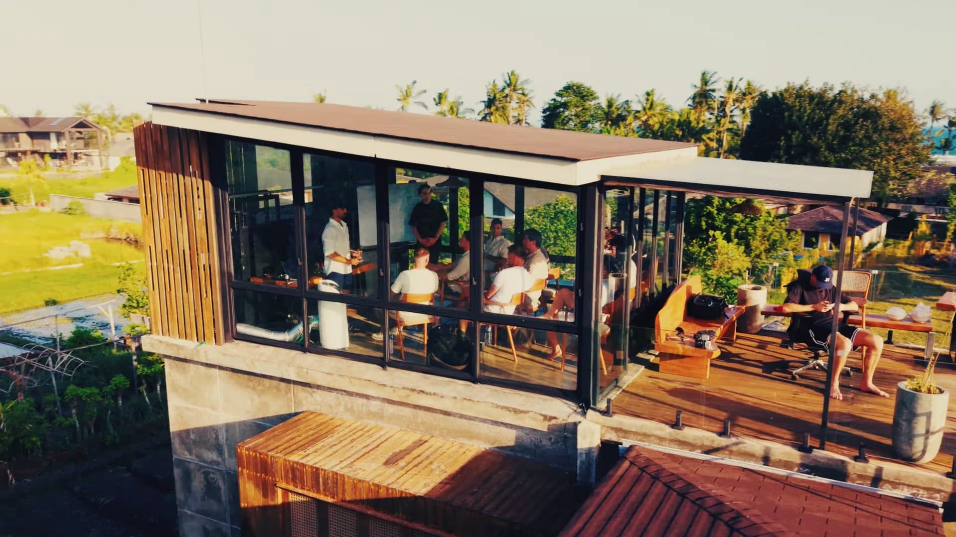 A workshop in progress, seen from outside the glass room at dusk.