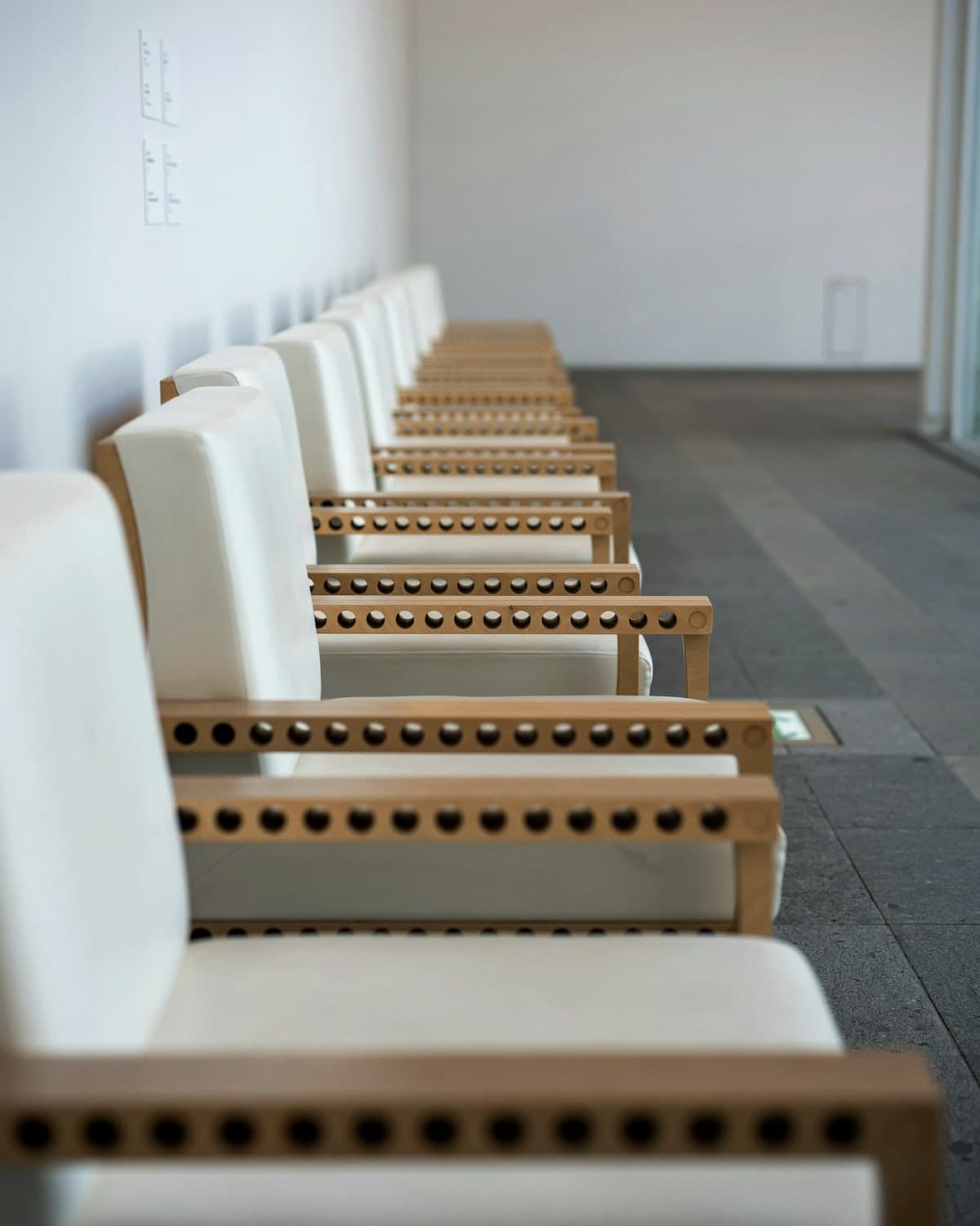 A row of white chairs with wooden frames, waiting