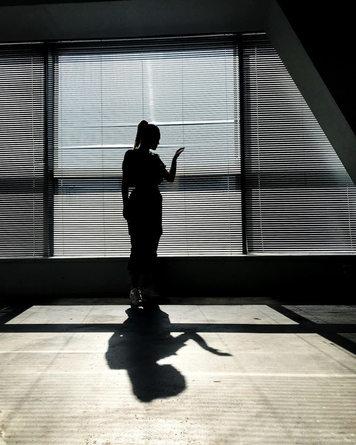 A woman on a call at a tall office window, in silhouette